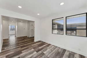 Empty room featuring a textured ceiling and dark hardwood / wood-style floors