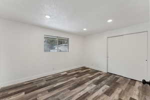 Unfurnished bedroom featuring dark hardwood / wood-style flooring, a textured ceiling, and a closet