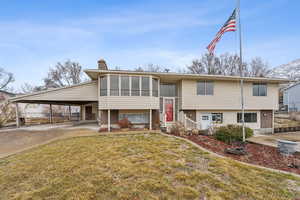 Split foyer home with a front lawn, a sunroom, and a carport