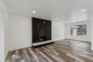 Unfurnished living room with a fireplace, wood-type flooring, and a textured ceiling