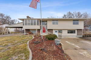 Split foyer home featuring a front yard, a sunroom, and a carport