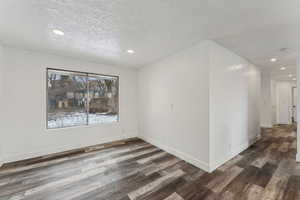 Spare room featuring a textured ceiling and dark hardwood / wood-style floors