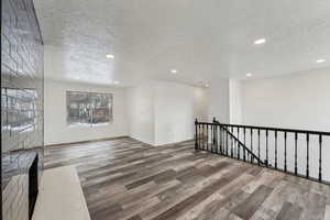 Empty room with a textured ceiling and hardwood / wood-style floors