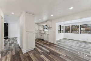 Kitchen featuring dishwasher, dark wood-type flooring, sink, and white cabinets