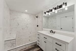 Bathroom featuring hardwood / wood-style floors, a tile shower, and vanity