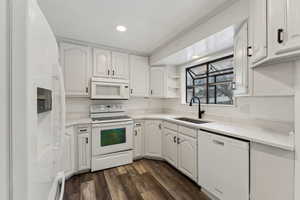 Kitchen featuring sink, white appliances, white cabinetry, and dark hardwood / wood-style flooring