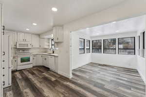 Kitchen with white appliances, white cabinets, and dark hardwood / wood-style floors