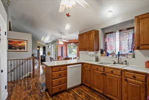 Kitchen with kitchen peninsula, sink, vaulted ceiling, dishwasher, and dark wood-type flooring