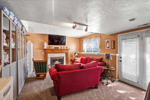 Living room featuring a fireplace, carpet floors, and a textured ceiling