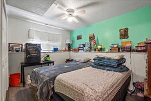 Bedroom featuring hardwood / wood-style flooring, ceiling fan, and a textured ceiling