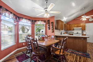 Dining area featuring ceiling fan, vaulted ceiling, and dark hardwood / wood-style flooring