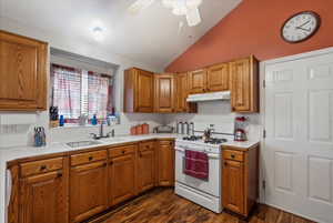 Kitchen with lofted ceiling, ceiling fan, dark hardwood / wood-style flooring, sink, and white gas range oven