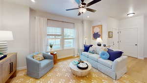 Living room with ceiling fan and light hardwood / wood-style floors