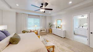 Carpeted bedroom with ceiling fan, ensuite bath, a tray ceiling, and sink