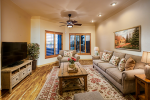 Virtually staged living room area featuring beautiful flooring and lighted ceiling fan