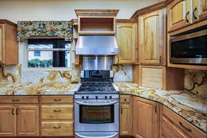 Kitchen featuring upgraded cabinets and storage options, long granite counters with breakfast bar. a sink with reverse osmosis system, under cabinet range hood, recessed lighting, beautiful iron chandelier, stainless steel appliances, gas stove, appliance