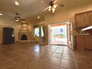 Unfurnished living room featuring ceiling fan, a large fireplace, and tile patterned flooring