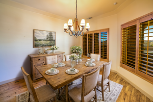 Virtually staged dining space featuring light wood-style floors, unique western style chandelier and plantation shutters