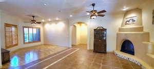 Unfurnished living room with ceiling fan, a large fireplace, and tile patterned floors