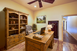 Virtually staged spacious office including a built in safe with lighted ceiling fan, recessed lighting and wood shutters on the windows