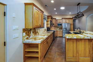 Kitchen featuring upgraded cabinets and storage options, long granite counters with breakfast bar. a sink with reverse osmosis system, under cabinet range hood, recessed lighting, beautiful iron chandelier, stainless steel appliances, appliance garage and