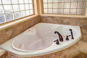 Primary bathroom with a jetted tub and custom tile area