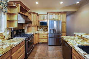 Kitchen featuring upgraded cabinets and storage options, long granite counters with breakfast bar. a sink with reverse osmosis system, under cabinet range hood, recessed lighting, beautiful iron chandelier, stainless steel appliances, appliance garage and
