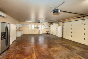 Garage with water softer, security system, door going to the back yard patio area, refrigerator and additional cabinetry.