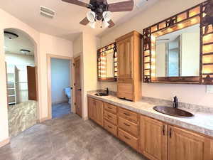 Bathroom with toilet, vanity, and ceiling fan