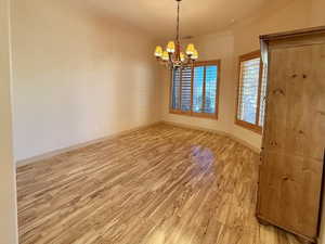 Empty room with an inviting chandelier and wood-type flooring