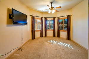 Virtually staged large guest bedroom on guest wing side, with beautiful wood shuttered windows, lighted ceiling fan, and closet