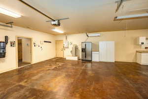 Garage with water softer, security system, door going to the back yard patio area, garage door opener, refrigerator and additional cabinetry.