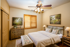 Virtually staged 3rd bedroom, carpeted with closet and wood shuttered window.