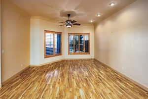 Living room area located opposite of the grand family area, featuring beautiful flooring and lighted ceiling fan