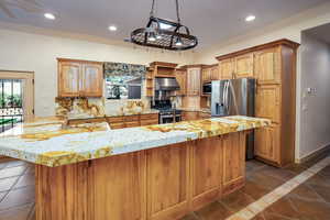 Kitchen featuring upgraded cabinets and storage options, long granite counters with breakfast bar. a sink with reverse osmosis system, under cabinet range hood, recessed lighting, beautiful iron chandelier, stainless steel appliances, appliance garage and