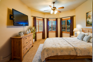 Virtually staged large guest bedroom on guest wing side, with beautiful wood shuttered windows, lighted ceiling fan, and closet