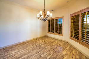 Large dining room with light wood-style floors, unique western style chandelier and plantation shutters