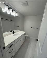 Bathroom featuring a shower, toilet, a textured ceiling, and vanity