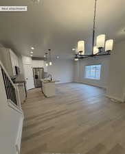 Kitchen with a center island with sink, appliances with stainless steel finishes, decorative light fixtures, sink, and white cabinetry