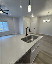 Kitchen with white cabinets, sink, black dishwasher, and decorative light fixtures