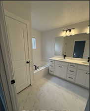 Bathroom featuring a bath, a textured ceiling, and vanity