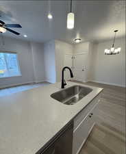 Kitchen featuring sink, light wood-type flooring, decorative light fixtures, ceiling fan with notable chandelier, and white cabinets