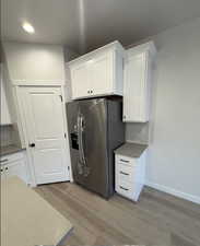 Kitchen with white cabinetry and stainless steel refrigerator with ice dispenser