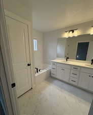 Bathroom with vanity, a bathtub, and a textured ceiling