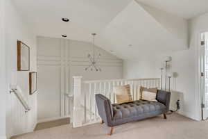 Sitting room with an inviting chandelier, carpet, and vaulted ceiling