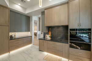 Kitchen featuring gray cabinets, black appliances, tasteful backsplash, and light brown cabinetry