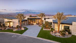 View of front of house with a mountain view, a garage, and a lawn