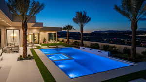 Pool at dusk featuring a patio area and an in ground hot tub