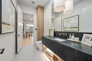 Bathroom featuring vanity, toilet, and backsplash