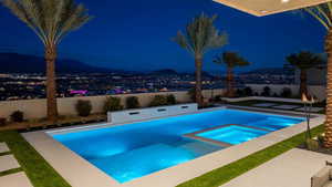 Pool at twilight featuring an in ground hot tub and a water view